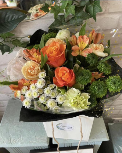 Sunset Garden Charm - A warm and inviting arrangement inspired by the rich hues of a glowing sunset. Vibrant orange tones blend effortlessly with soft creams and fresh greens, creating a lively yet balanced display. The mix of textures and layered elements gives it a natural, garden-picked feel, while the sleek presentation adds a modern touch. Perfect for uplifting occasions or sending a cheerful message, this design radiates warmth, energy, and joyful elegance.